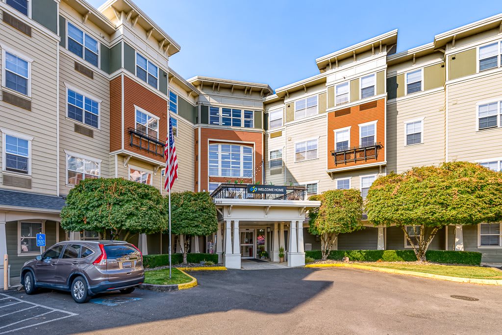 Exterior view of a multistory residential building with an American flag at the entrance.