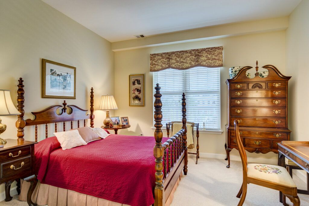 A cozy bedroom with traditional decor, featuring a wooden bed frame and red bedding.
