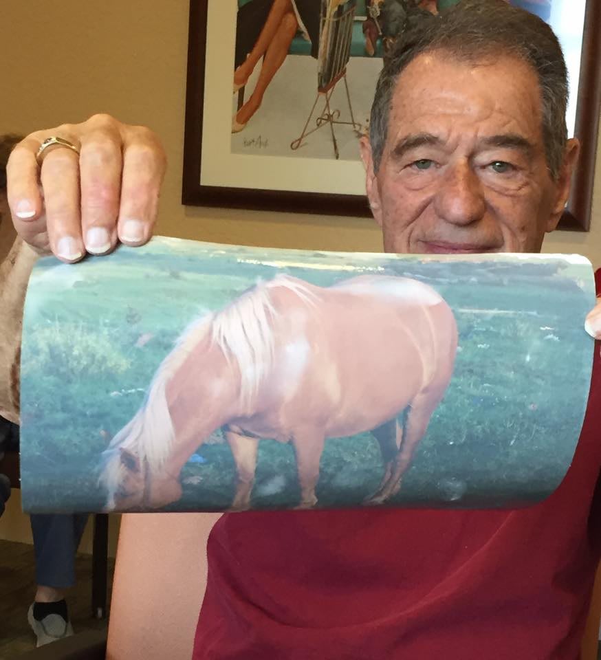 A man is holding an object displaying an image of a horse.