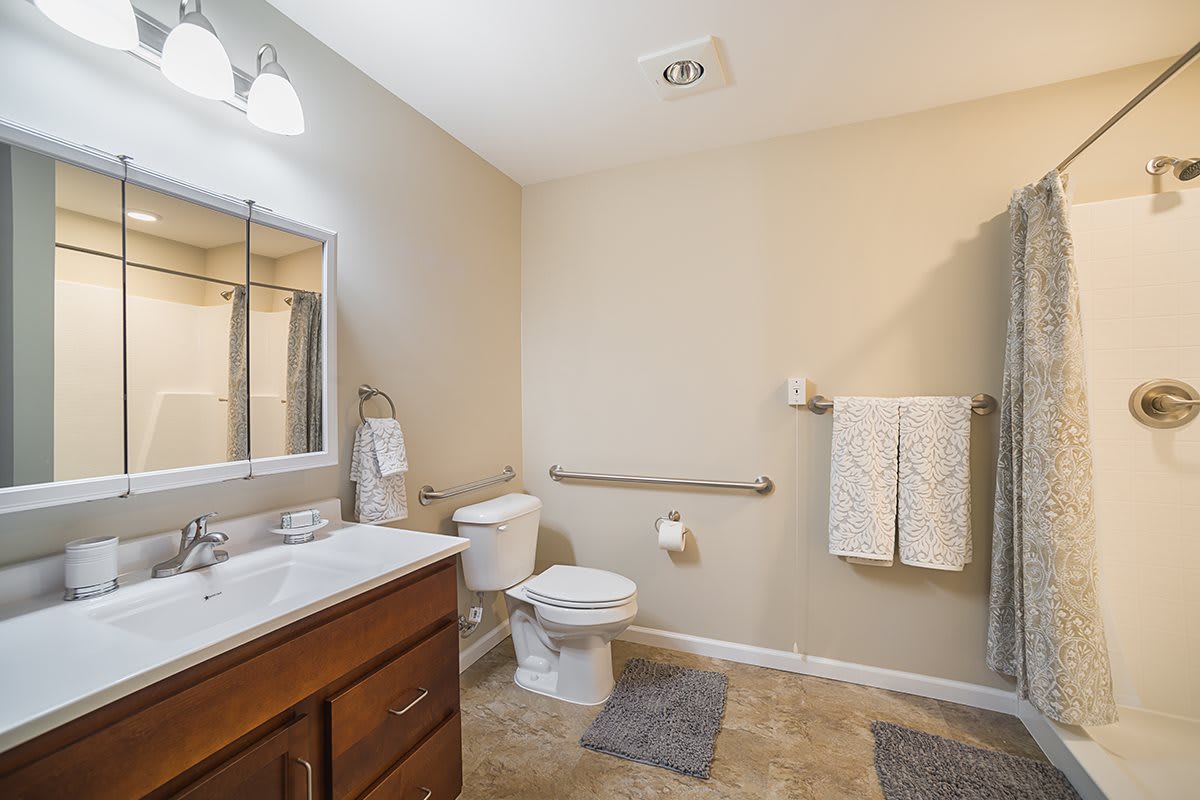 A modern and clean bathroom with a sink, toilet, mirror, and towel rack.