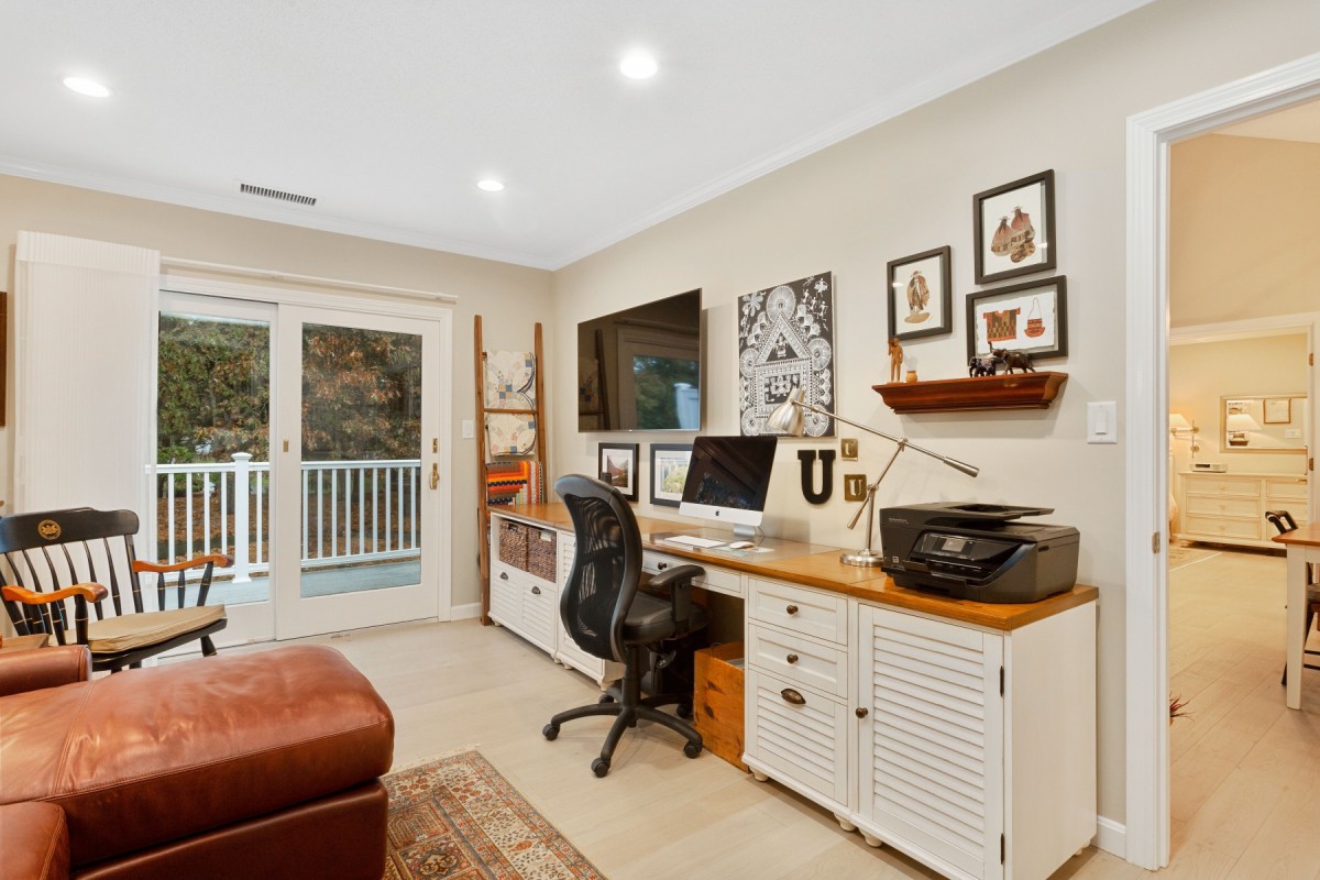 A cozy home office setup with a desk, computer, chair, and decorative artwork.