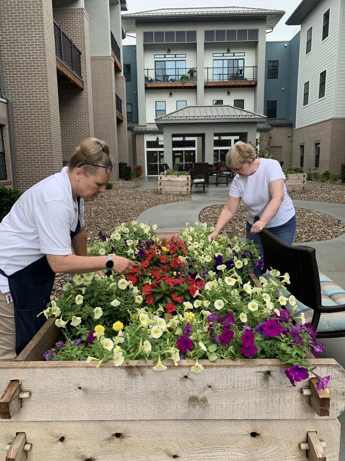 Two people tending to a raised flower bed in an urban setting.
