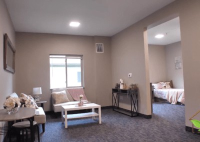 A cozy living room with a sofa and table, adjacent to a bedroom.