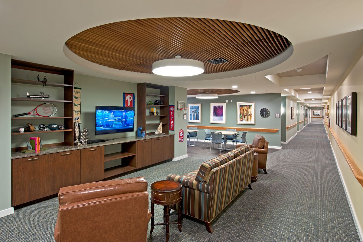 A cozy lounge area featuring comfortable seating, a television, and colorful artwork on the walls.