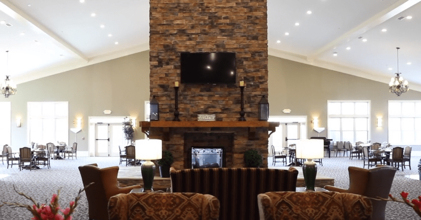 A modern lobby featuring a central brick fireplace with a mounted television and comfortable seating arrangements.