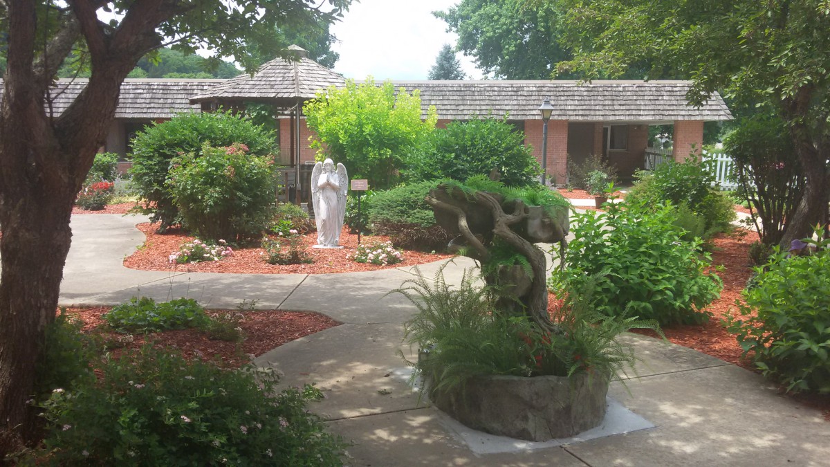 A serene garden with a statue and well-maintained landscaping.