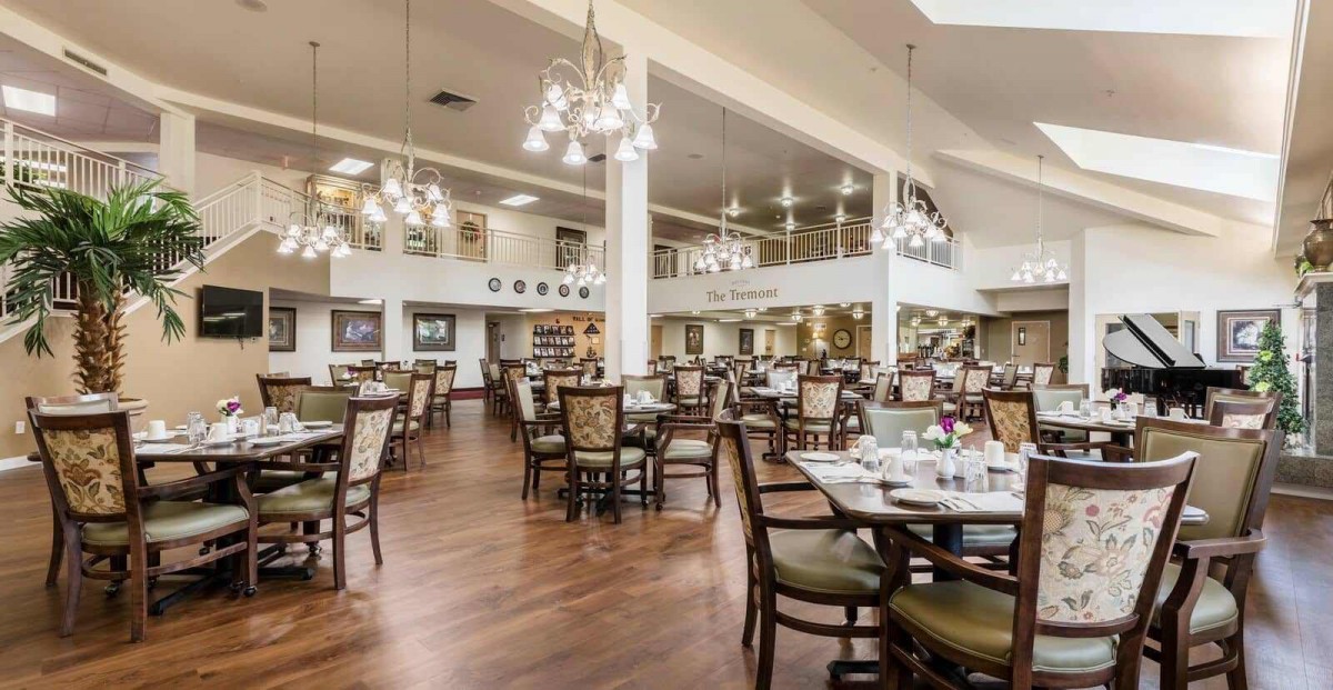An elegant dining room with neatly arranged tables and chairs, adorned with chandeliers.