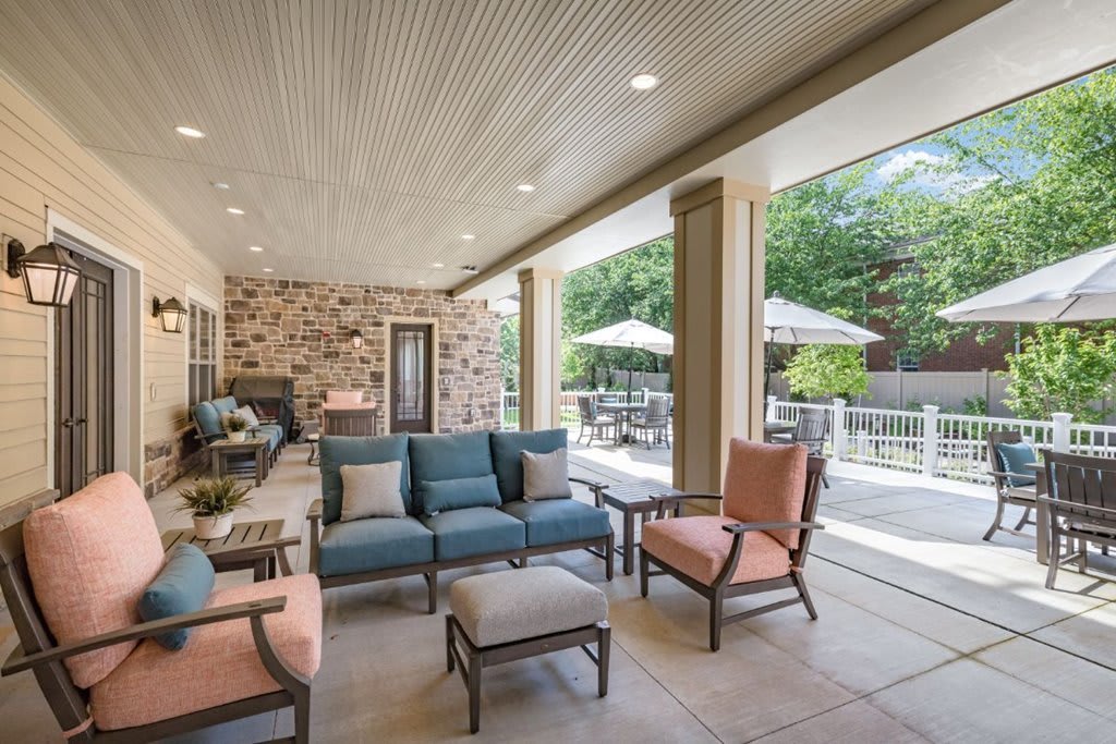 A spacious covered patio featuring comfortable outdoor seating with views of a well-maintained garden.