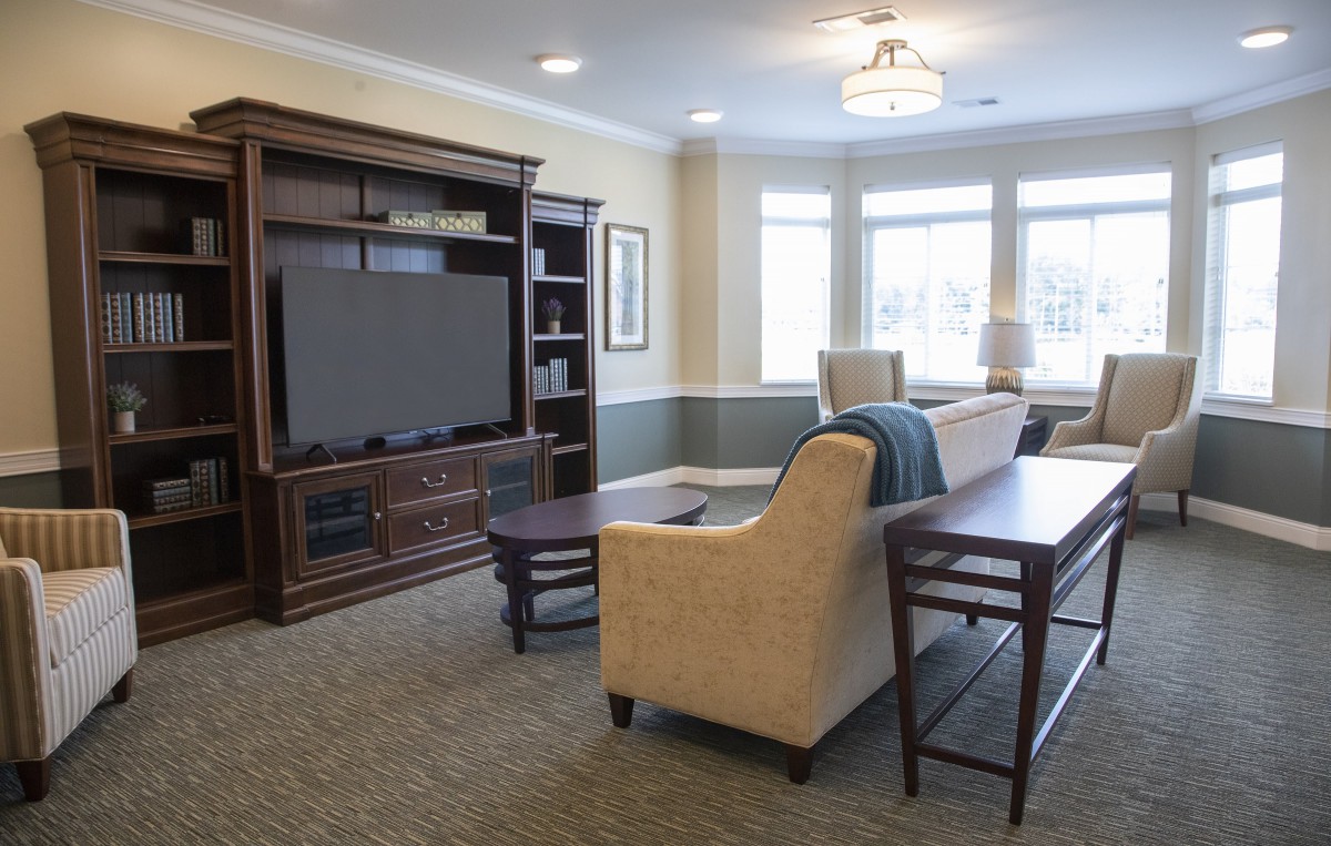 A cozy living room with an entertainment center, sofa, and large windows.
