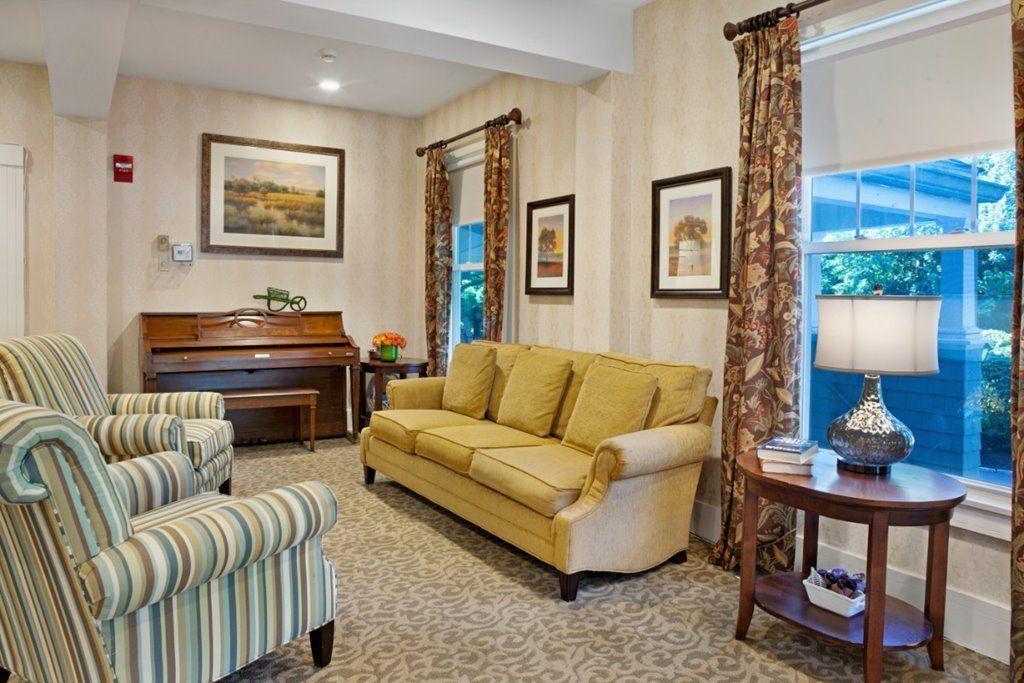 A cozy living room with a sofa, armchairs, and a piano.