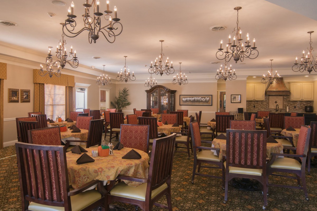 An elegant dining room with chandeliers and neatly arranged tables and chairs.