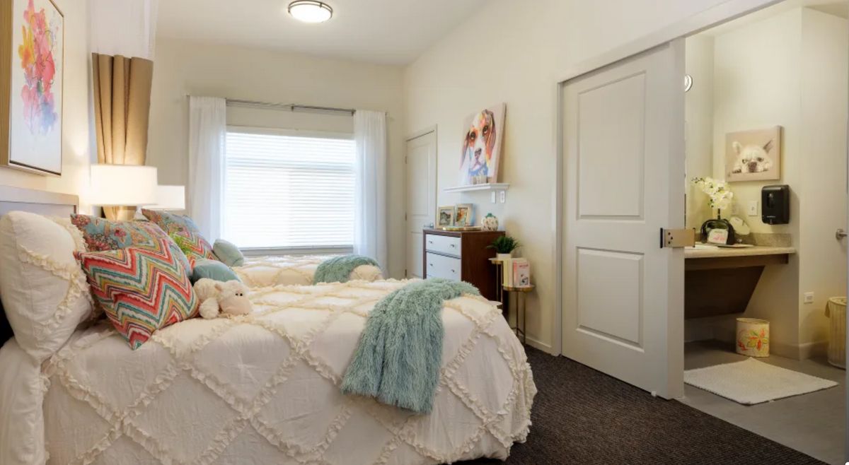 A cozy bedroom with stylish decor and a large window allowing natural light.
