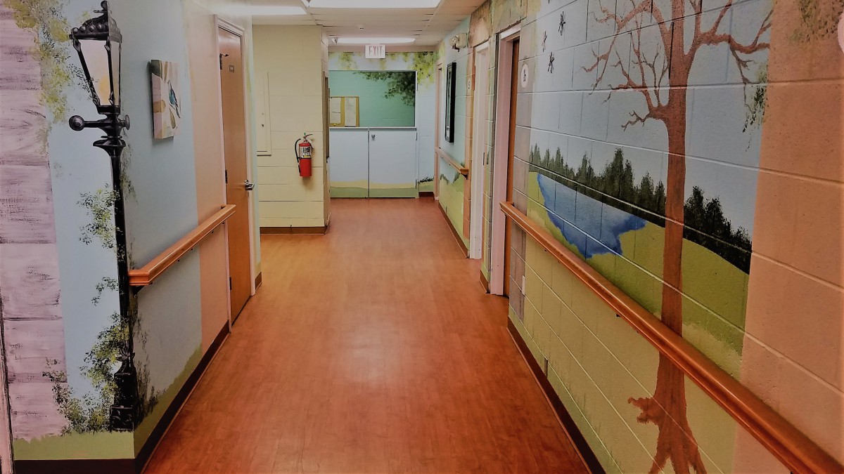 A colorful hospital corridor with murals on the walls.