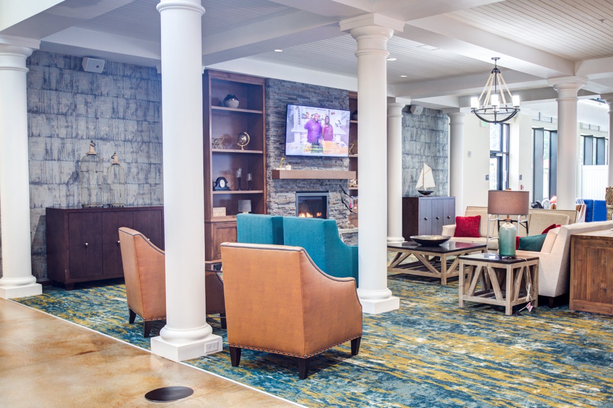 A modern lobby with comfortable seating, featuring a television and decorative columns.