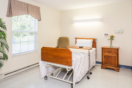 A clean and organized hospital patient room featuring an adjustable bed and natural light.