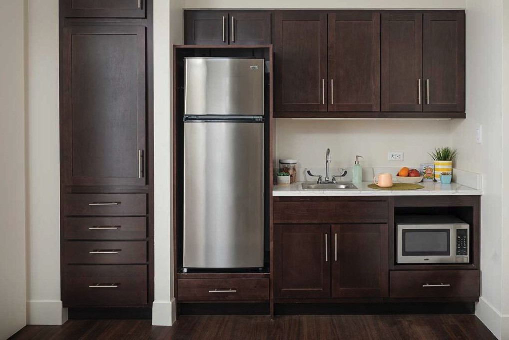 A modern kitchen with dark wood cabinets and a stainless steel refrigerator.