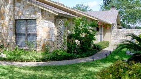 A charming residential house with stone features, surrounded by vibrant landscaping.