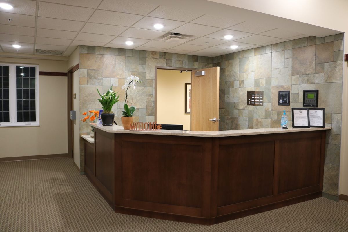 A well-lit office reception area with a wooden desk and decorative plants.