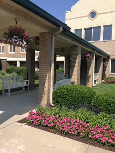 A landscaped garden area with flowers and a bench in front of a building.