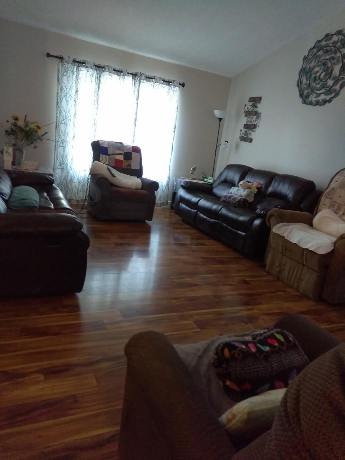 A cozy living room with sofas and recliners on a hardwood floor.
