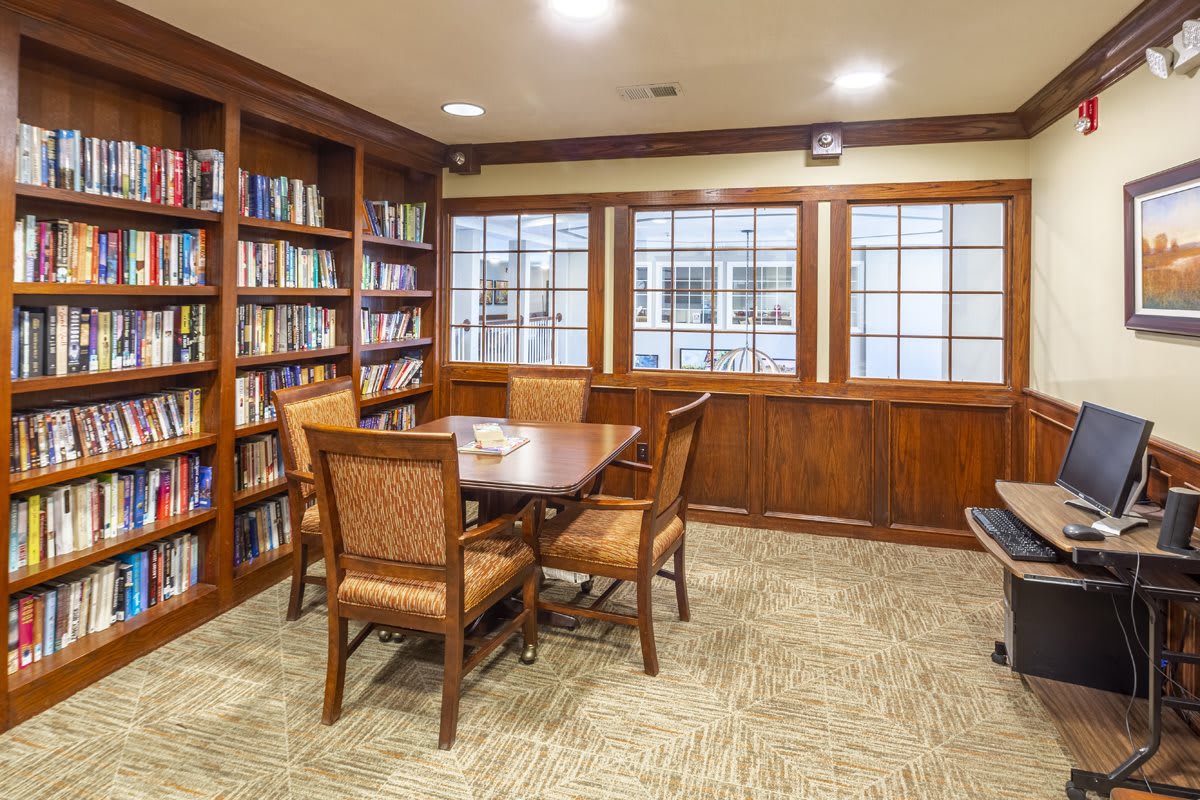 A cozy library setting with bookshelves, a wooden table, and chairs.