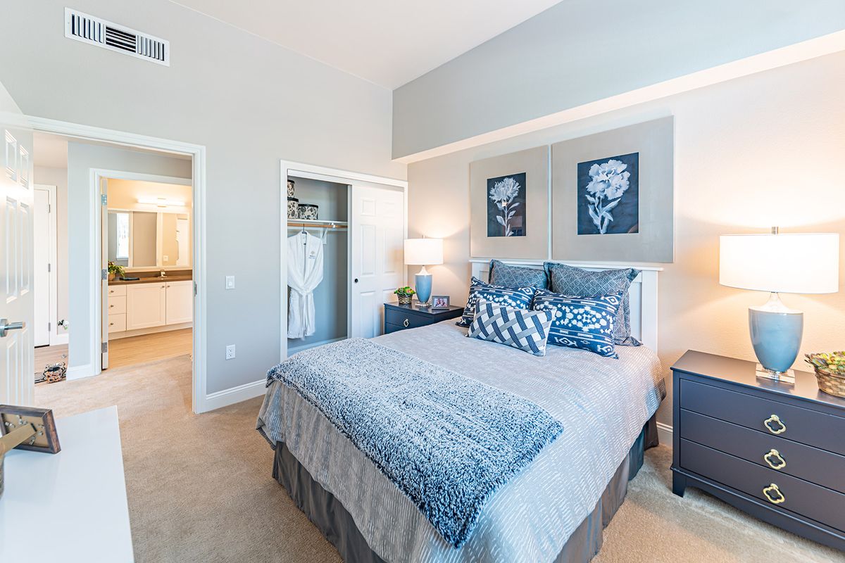 A modern bedroom with stylish decor, featuring a comfortable bed, artwork above the headboard, and a closet in the corner.