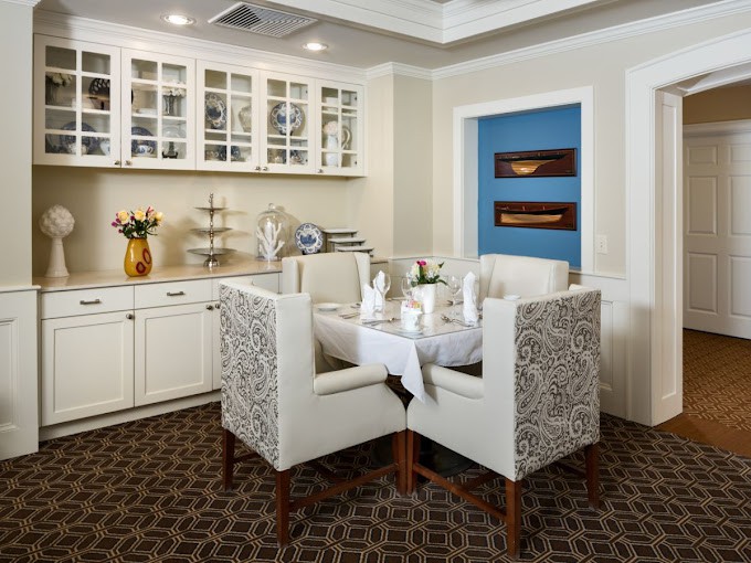 An elegantly set dining area with upholstered chairs and a decorative cabinet.