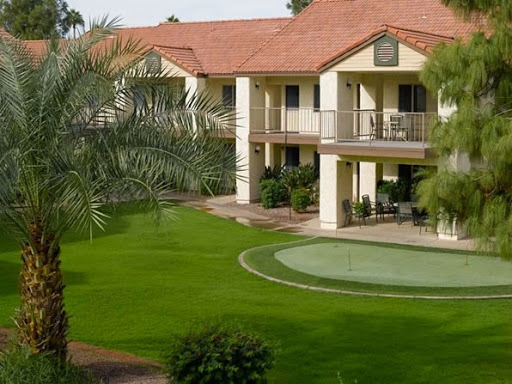 A view of a residential building with lush green landscaping and a small putting green.