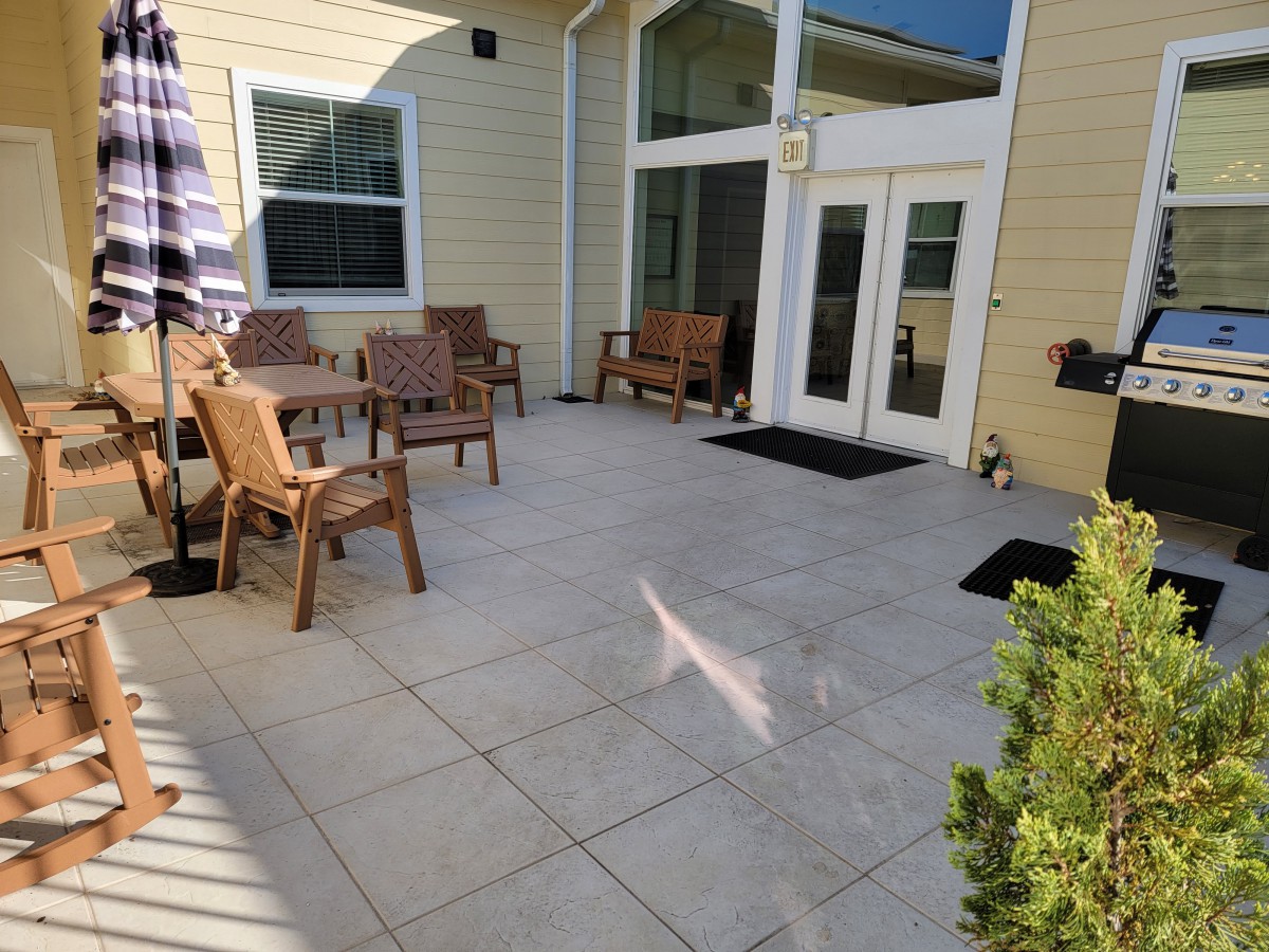 A sunny patio with outdoor furniture including chairs, a table, and benches.