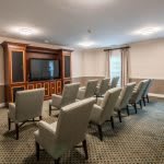A small conference room with rows of chairs facing a large television.