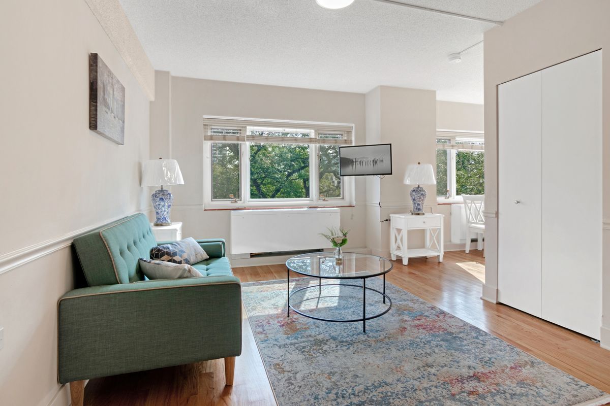 A cozy living room with a green sofa, stylish coffee table, and large windows allowing natural light to brighten the space.