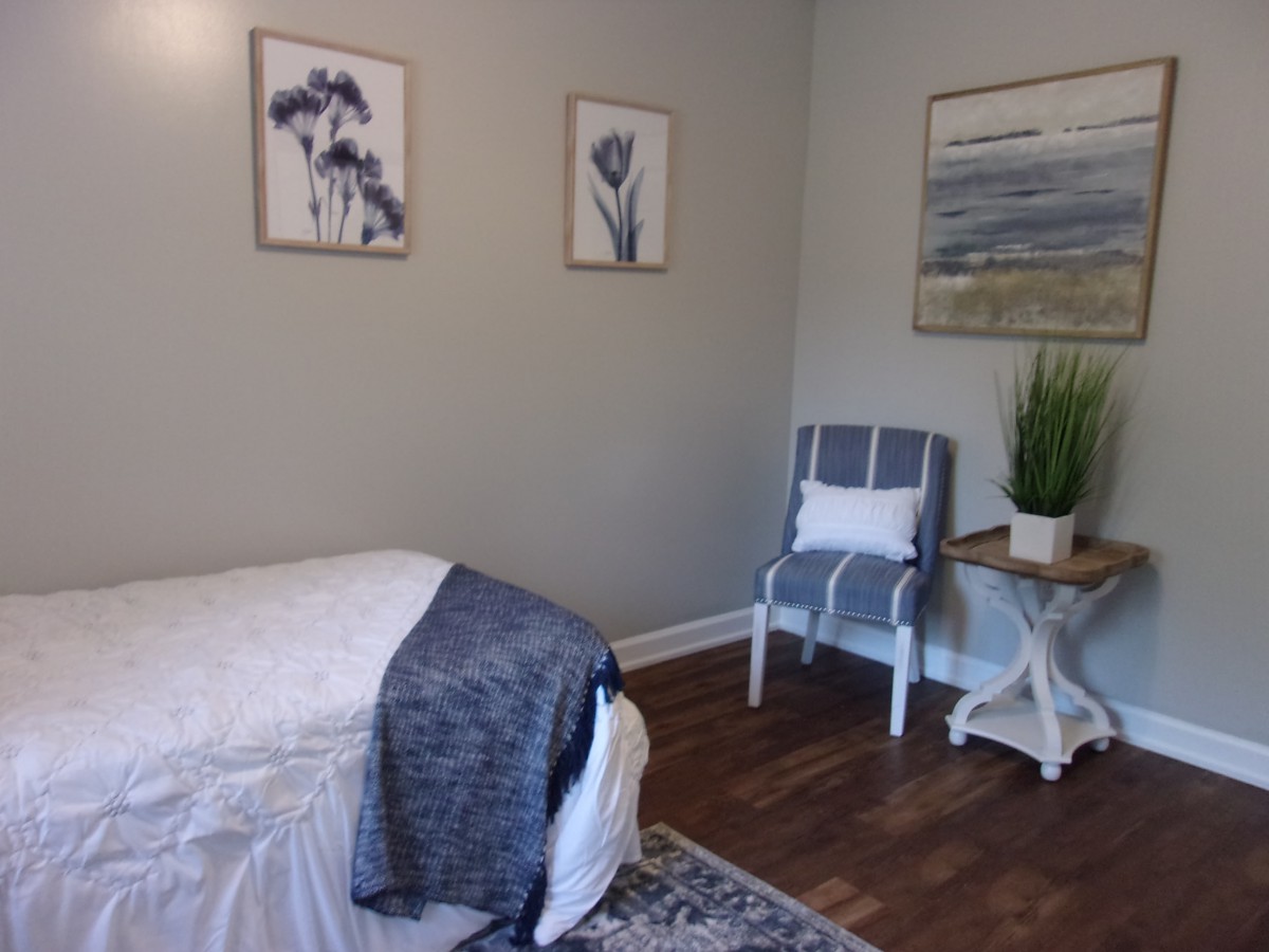 A serene spa room with a massage bed, decorated with calming artwork and cozy furnishings.