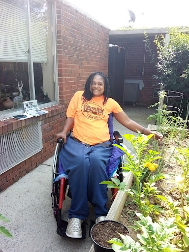 A joyful individual enjoying the beauty of gardening while seated in a wheelchair.