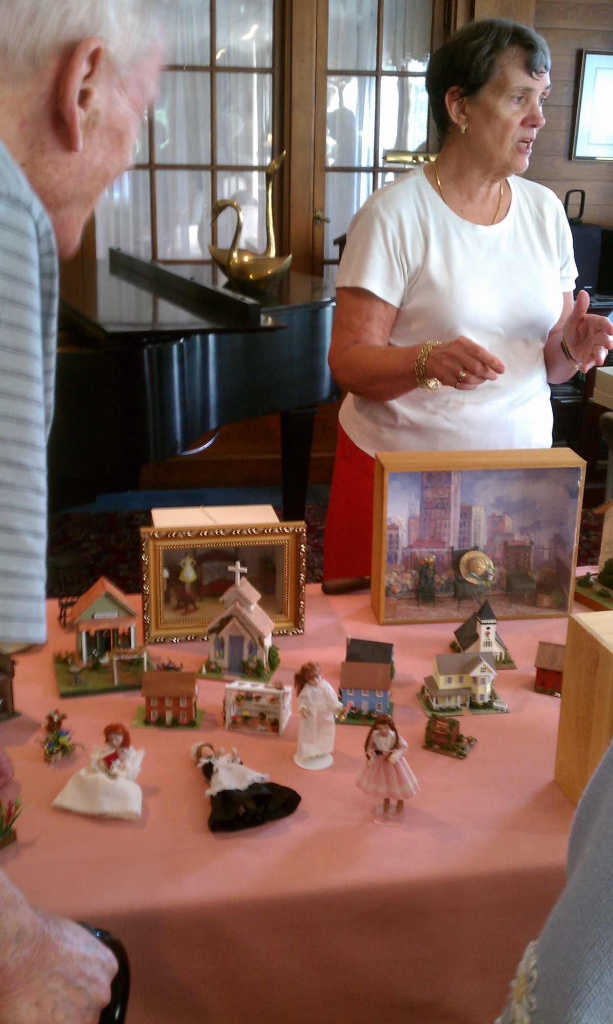 A tabletop display featuring various miniature dolls and figurines being showcased at a craft or sales event.