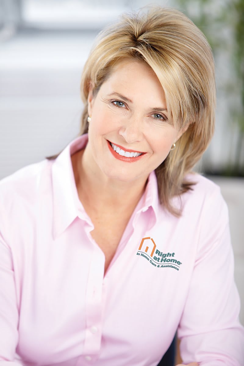 A smiling woman in a professional setting wearing a branded shirt.