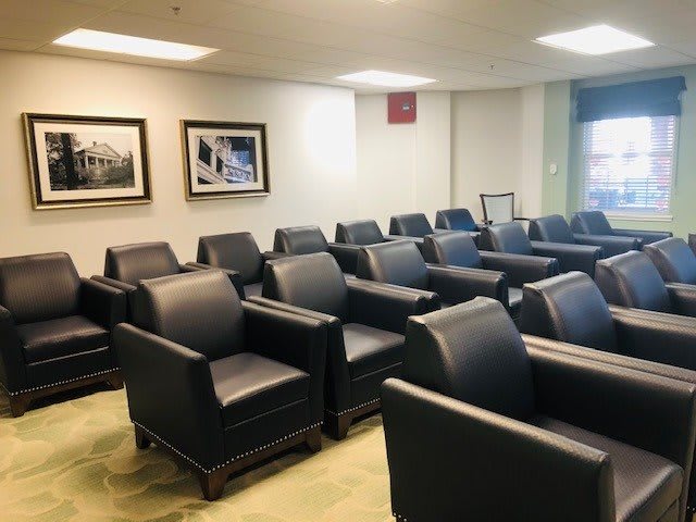 A quiet waiting room with several rows of comfortable armchairs.