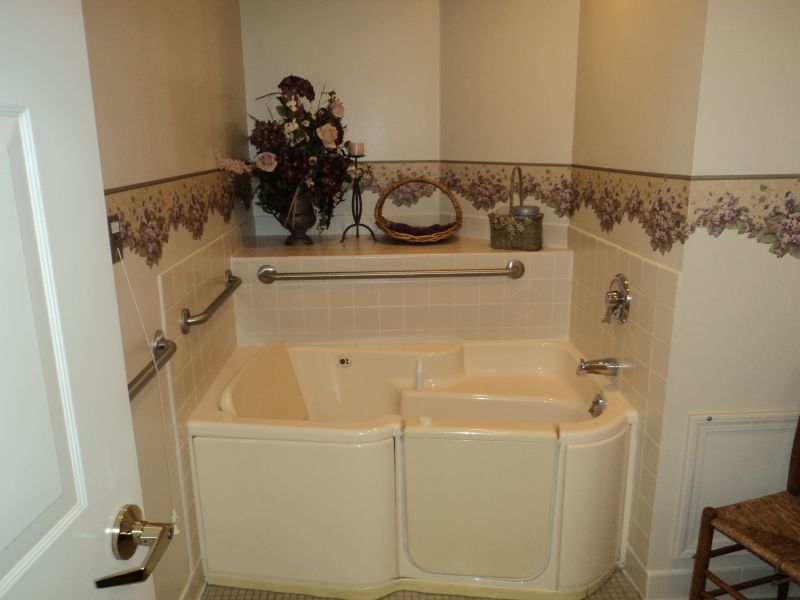 A cozy bathroom featuring a walk-in bathtub with safety bars and decorative floral accents.