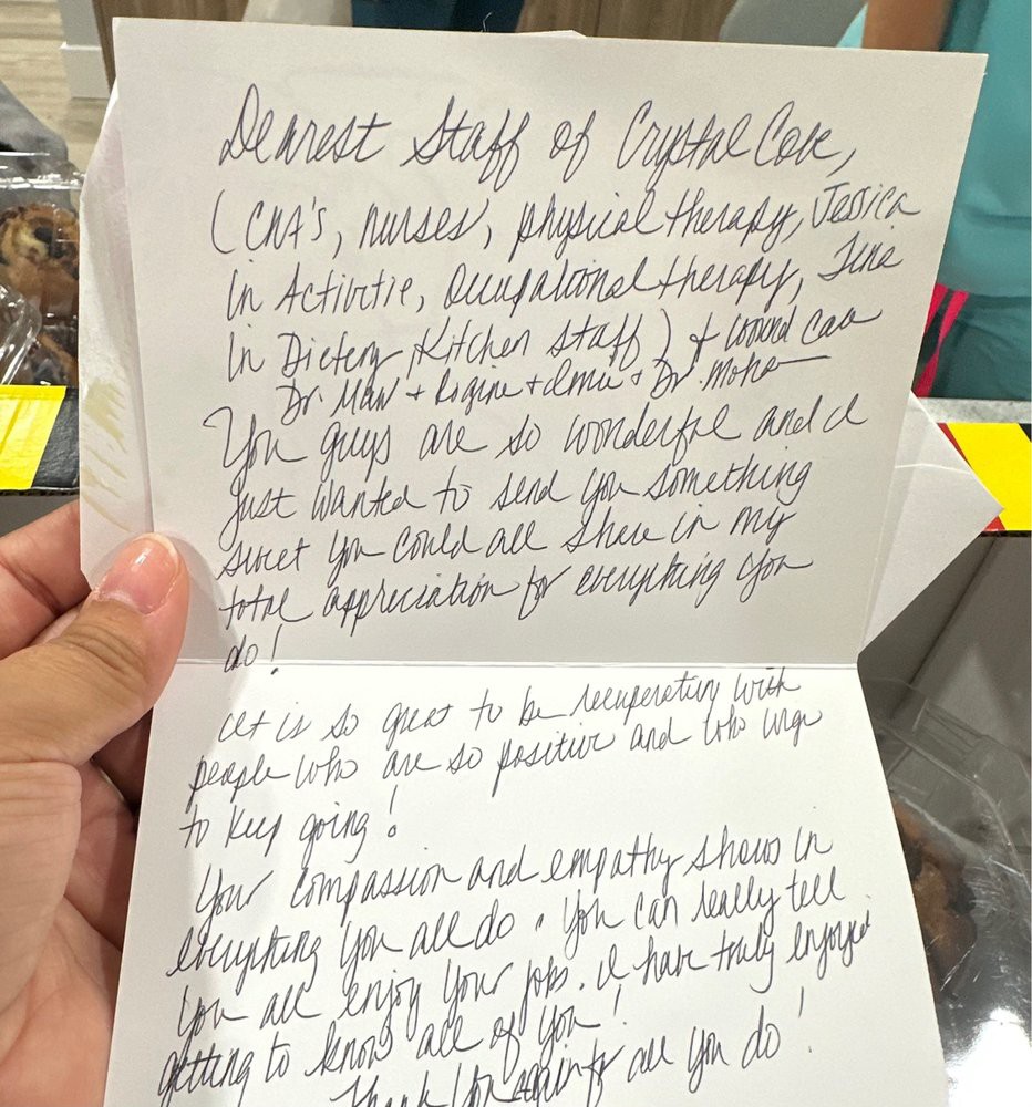 A person holding a handwritten letter with cursive text on paper.