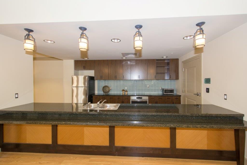 Modern kitchen with wood cabinets and pendant lighting.