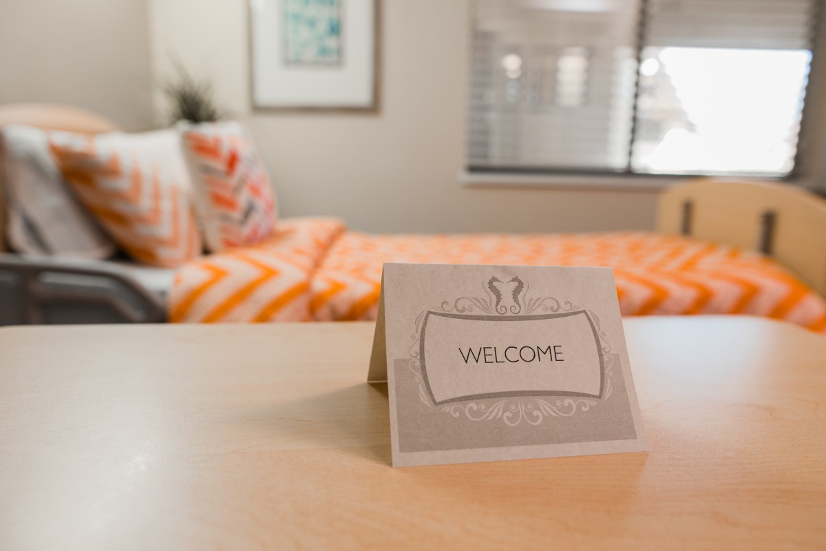 A welcoming card on a table in a cozy bedroom.