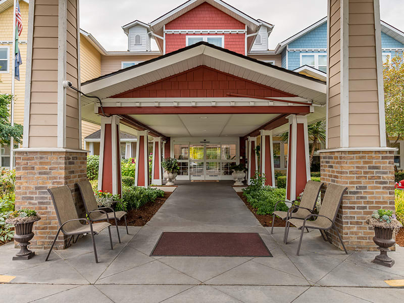 Covered entrance with seating area and landscaping.