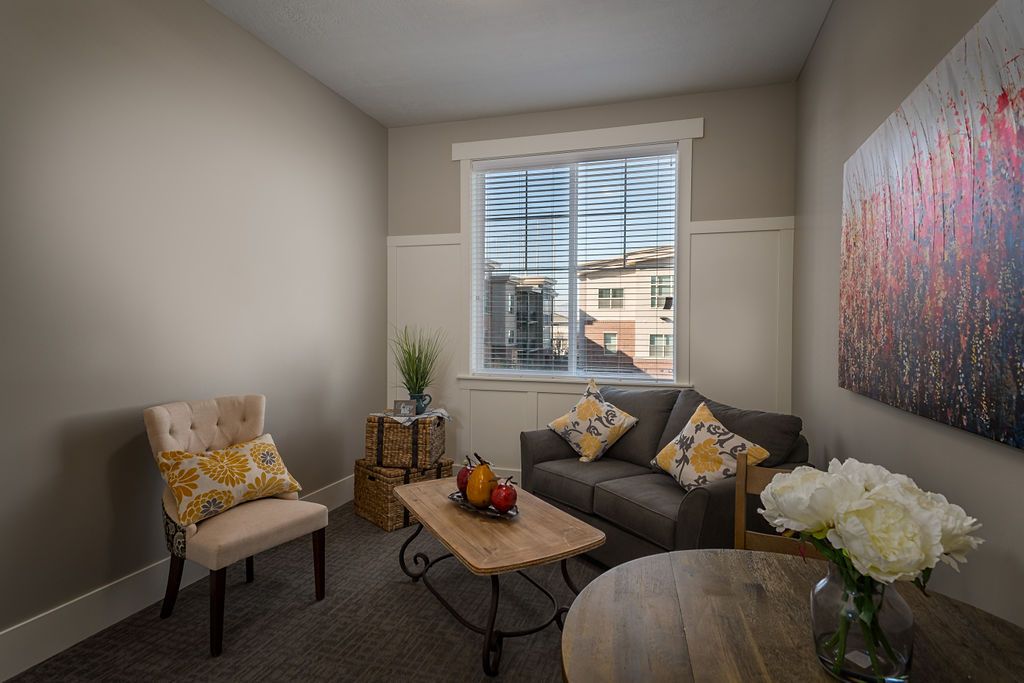 A cozy living room with a sofa, chairs, and a window letting in natural light.