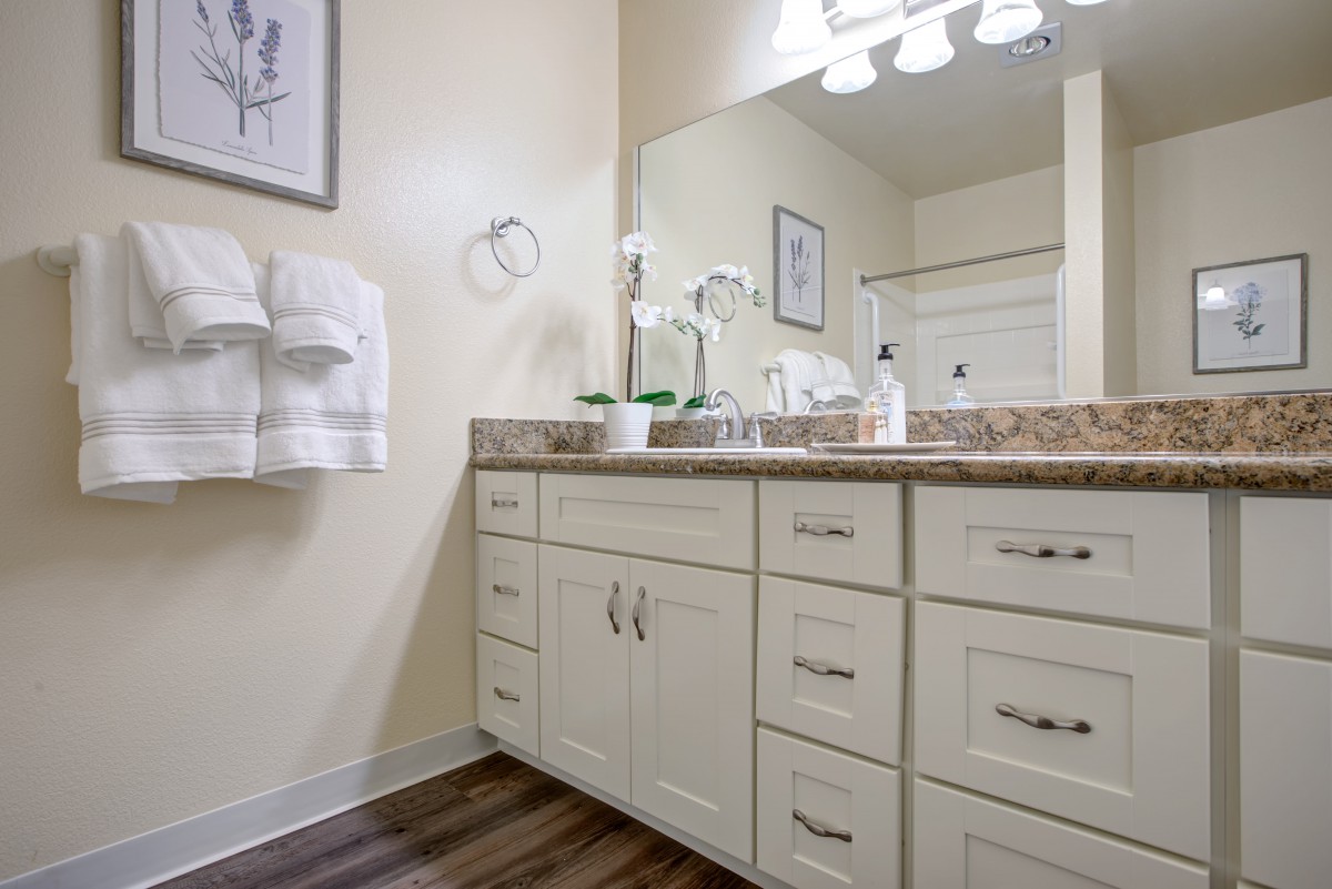 A modern bathroom with a large vanity, mirror, and neatly arranged towels.