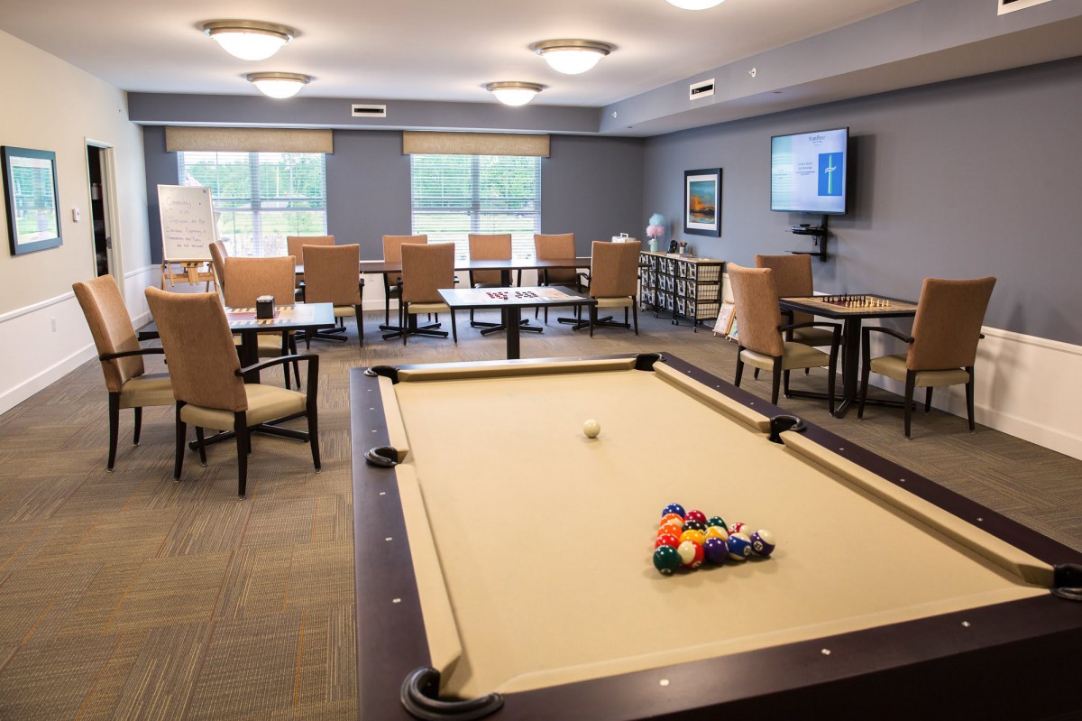 A spacious recreation room featuring a pool table and comfortable seating.