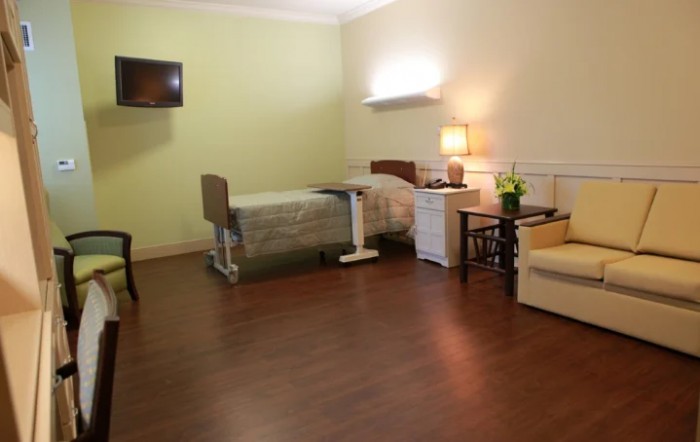 A well-organized hospital room with a bed, furniture, and a television.