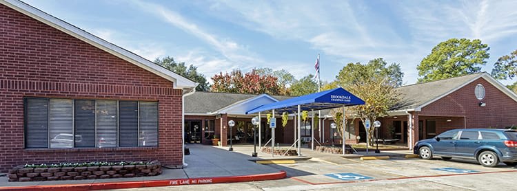 A building with a blue awning at the entrance next to a parking lot and an American flag.