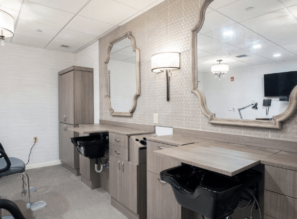 A modern salon interior featuring styling stations with mirrors, sinks, and chairs.