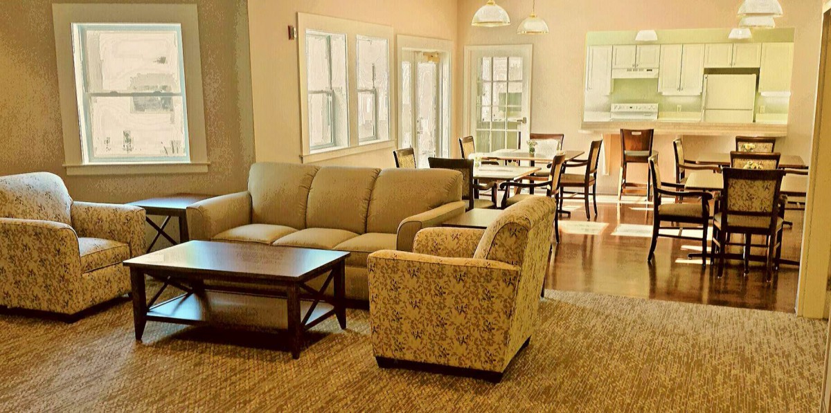 A cozy living room with a sofa, armchair, and dining area.