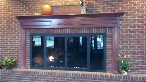 A cozy fireplace with a wooden mantel and decorative items, set against a brick wall.