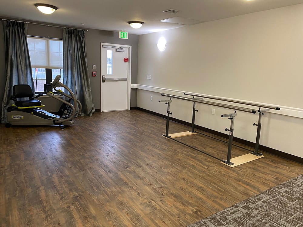 A physical therapy room with parallel bars and exercise equipment.